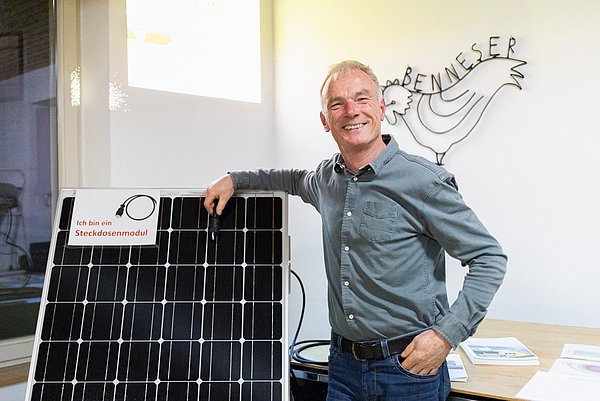 Ulrich Wolski vor einem Balkonkraftwerk mit Solarpanelen
